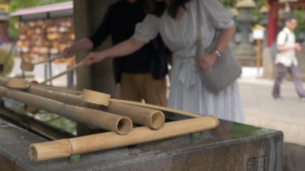 上野の寺院で手を浄化するために竹の柄杓を使って人々のショットを閉じる2つの動き — ストック動画