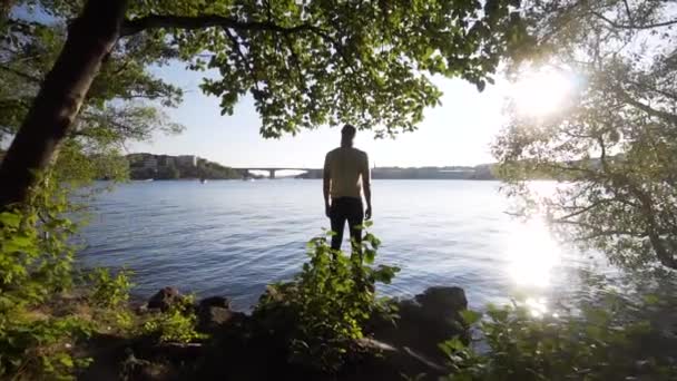 Ένας Ψηλός Λευκός Άντρας Στέκεται Δίπλα Ένα Κανάλι Στη Στοκχόλμη — Αρχείο Βίντεο