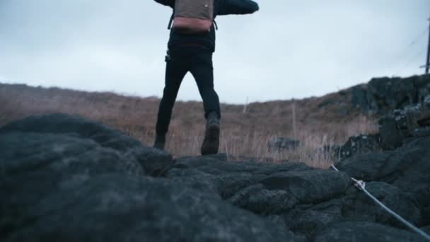アイスランドの岩の上をハイキングする若い男の超スローモーションショット — ストック動画
