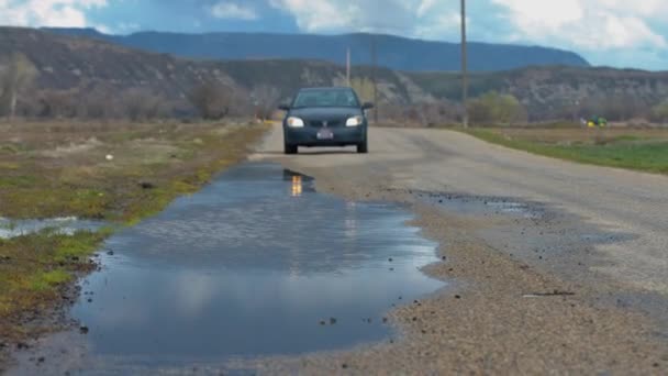 道路脇の水のプールを通って走るスピード違反の車噴水のように飛び散る — ストック動画