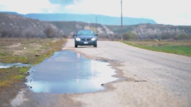 道路のせせらぎの水の中を車が通り過ぎると噴水のように水が飛び散っている — ストック動画