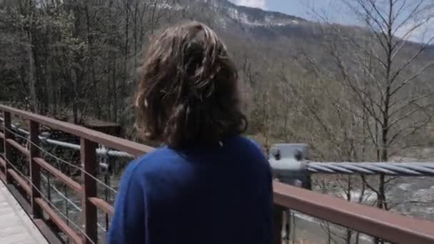 女孩在河山附近的一座桥上行走时 被山山的侧击倒了 — 图库视频影像