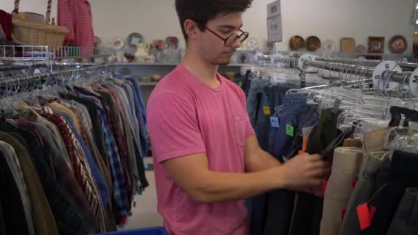 Fechar Menino Adolescente Olhando Através Rack Jeans Segunda Mão — Vídeo de Stock