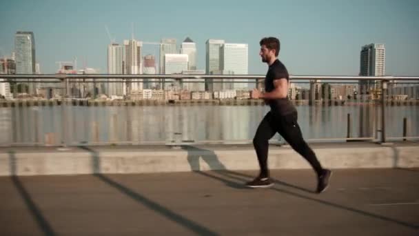 Man Joggar Slow Motion Med Canary Wharf Bakgrunden — Stockvideo