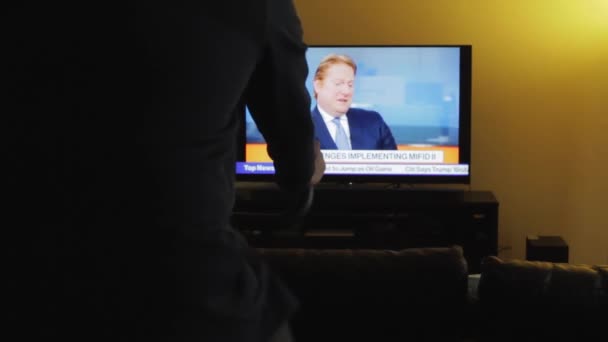 Ein Mann Sitzt Auf Einem Indoor Heimtrainer Während Fernsieht — Stockvideo