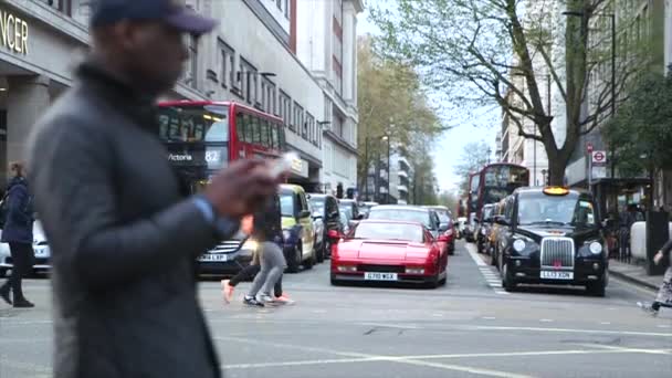 高価な車の前でロンドンの道路を横断するショッピングバッグを持つ人々 — ストック動画