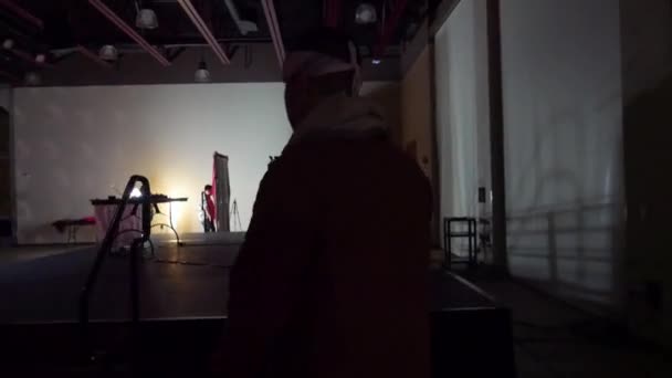 暗いステージを歩く男 彼がステージに上がるとカメラのパン — ストック動画