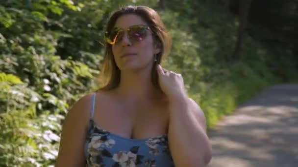 Жінка Блакитній Сукні Сонцезахисних Окулярах Йде Камери Вздовж Покинутої Лісової — стокове відео
