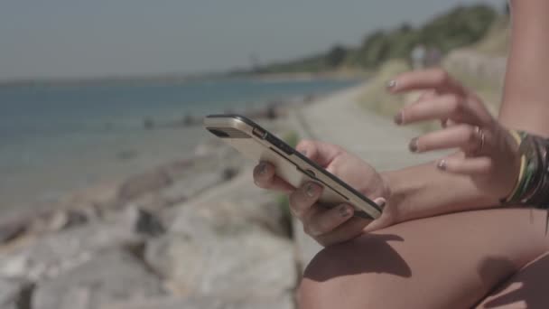 Młoda Atrakcyjna Kobieta Siedzi Plaży Wykorzystuje Swój Smartfon Dokonywania Zakupów — Wideo stockowe