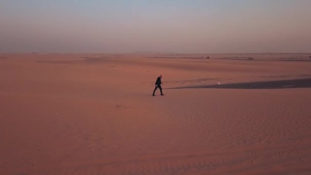 男は放棄された砂漠の道を歩いて 砂丘で どこの真ん中に覆われている 所在地 ドバイ アラブ首長国連邦 — ストック動画