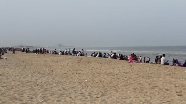 一群身份不明的人坐在海滨的码头边 享受着海风带来的闲暇 欣赏着舞动的海浪的美丽 — 图库视频影像