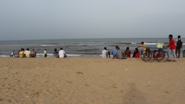 一群身份不明的人坐在海滨的码头边 享受着海风带来的闲暇 欣赏着舞动的海浪的美丽 — 图库视频影像