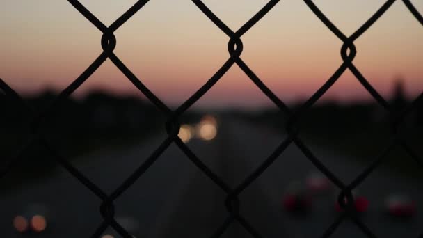 美しいボケの車のライトが下に行くフェンスを通って日没 — ストック動画
