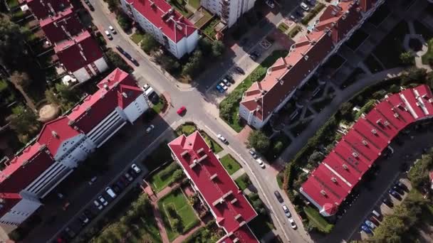 空中俯视城市上空的上空 显示有红色屋顶的居民区也停放着汽车 然后飞越公路穿越 向更多的家庭4K 跟随红色汽车 — 图库视频影像