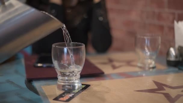 在餐馆里 侍者在杯子里倒水 一个女孩坐在桌旁的椅子上 — 图库视频影像