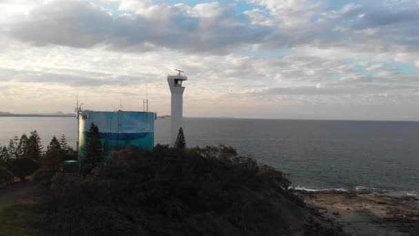 灯台日没を明らかにする 岩の上の灯台 オーストラリアのクイーンズランド州ポイント カートライト 株式ドローン映像 — ストック動画