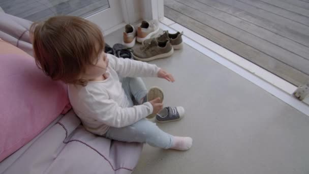 きれいな床にそれらをきちんと配置し きれいオフ靴を取って庭に開いてドアに豆袋に座っている若い子 — ストック動画