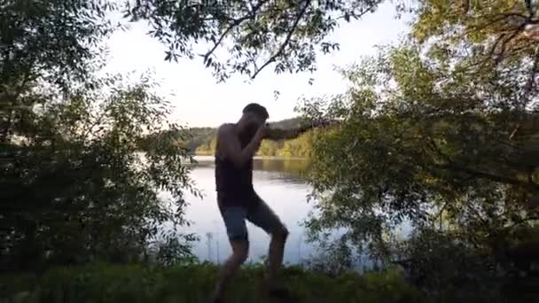 Ένας Ψηλός Λευκός Άντρας Γένια Κουτιά Σκιών Δίπλα Στη Λίμνη — Αρχείο Βίντεο