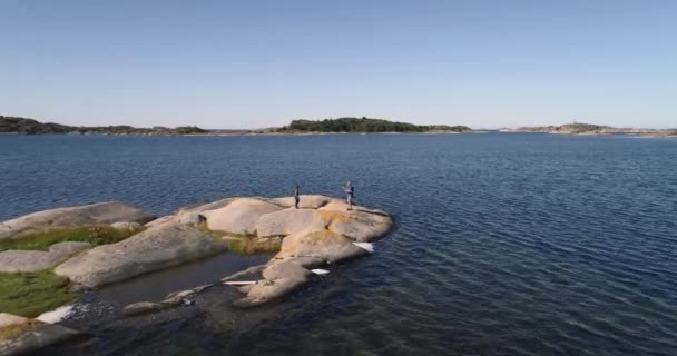 スウェーデンの岩の多い海岸線で魚を釣る準備をしている孫と祖父の空中 — ストック動画