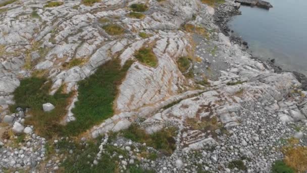 険しい岩から広い上方の空のパンは 完全に穏やかな海の牧歌的な穏やかな設定でノルウェーの孤立した明るい小さなトルンゲン灯台を明らかにする — ストック動画