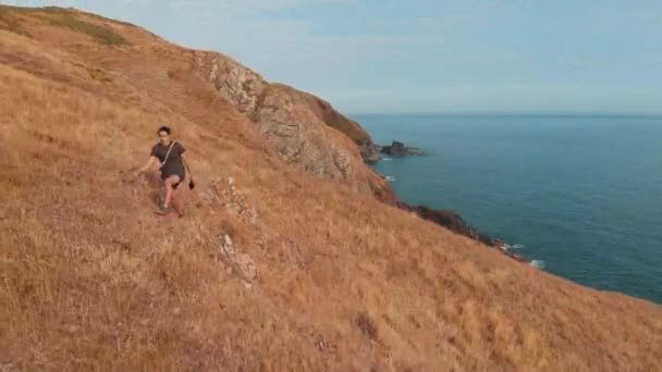 壮大な海岸沿いの崖に沿ってハイカーが歩く — ストック動画
