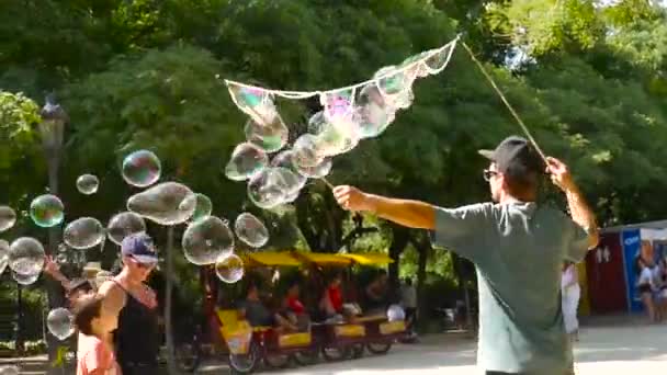 Muž dělá obrovské mýdlové bubliny se šťastnými dětmi hrát kolem něj v centru Barcelony.