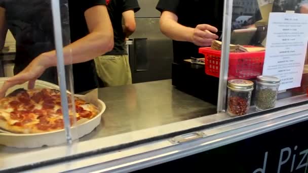 Sběr feferonkové pizzy z jídelního vozu a posypání chilli paprikou.