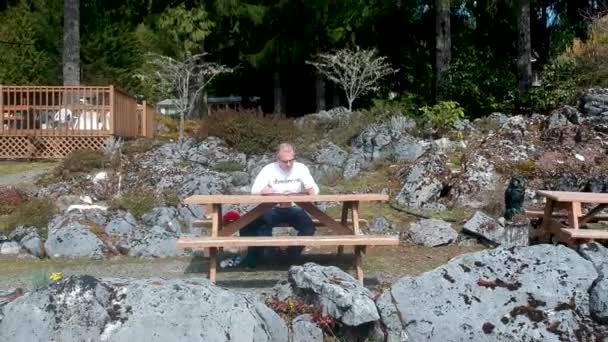 Man Die Een Boek Leest Een Picknicktafel Een Strand — Stockvideo