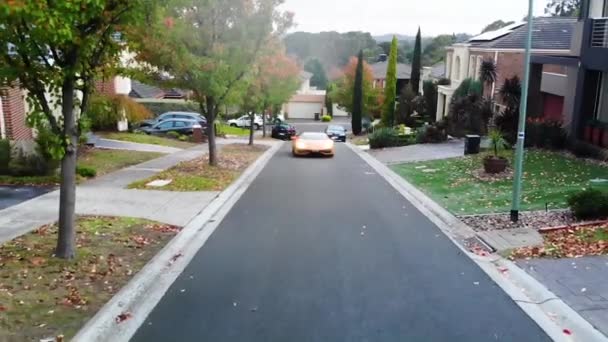 Lamborghini drives slowly down local street aerial slow motion, wipers on