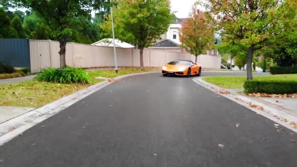 Orange Lamborghini驾驶着无人驾驶飞机缓缓驶过郊区的街道 — 图库视频影像