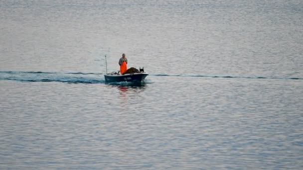 魚を捕まえた後に港に戻る小さな木製のボートに乗ってクロアチアの古い伝統的な漁師 スローモーションショット ボートは小さく 青色で 漁師は保護オレンジ色の服を着ている — ストック動画