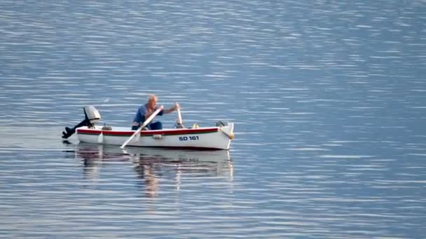 小さな木製のボートで魚を捕まえ それを販売するために港に戻って漕ぐクロアチアの古い伝統的な漁師は キャッチは小さな乱獲による小さく 伝統的な方法でハード生活を作ります — ストック動画