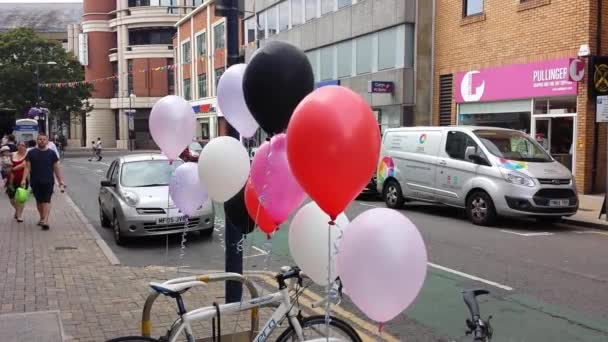 Fun červené, černé a bílé balónky plovoucí při připojení k jízdním kolům v Kingston-upon-Thames