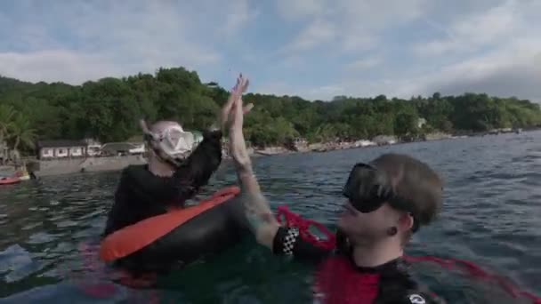 Couple Gives High Fives While Snorkeling Beach Buildings Lush Green — Stock Video