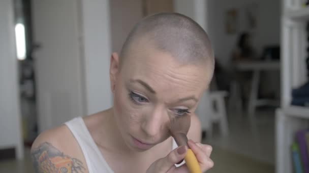 Hezká žena s velmi krátkými vlasy aplikuje svůj vlastní make-up v bílém tílku. Zpomalený pohyb.
