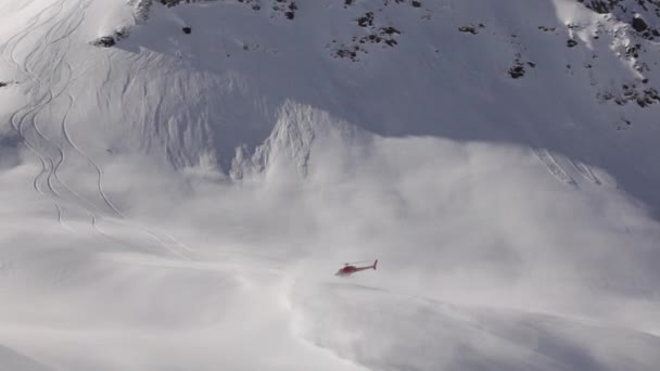 ヒマラヤでのヘリスキー作戦の一環としてヘリコプター インドのカシミールにある赤いヘリコプター 大きな山 たくさんの雪と木 — ストック動画