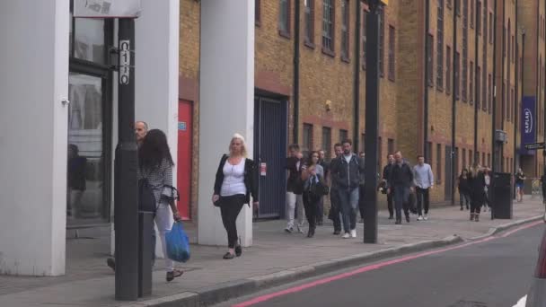 ingázók sétálnak egy forgalmas mellékutcában Londonban