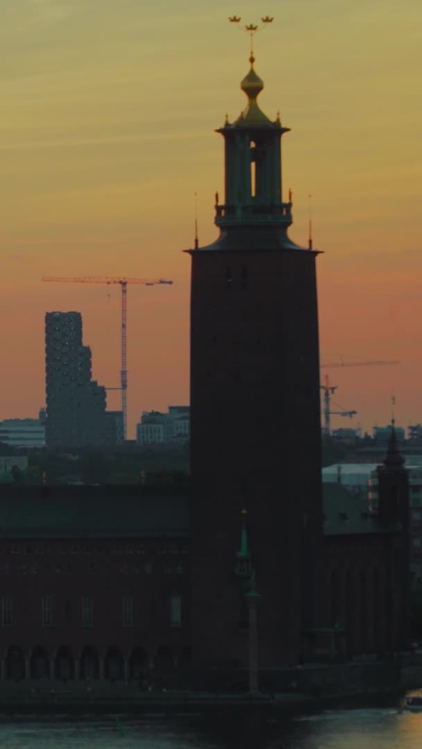 斯德哥尔摩湾市政厅的空中落日 人们步行 建筑起重机背景下的城市 垂直方向 — 图库视频影像