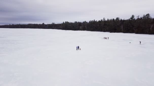 メイン州フィッツジェラルド池での氷釣りの空中ビューを取得します 釣りをしている人もいれば 氷の上を滑る人もいる — ストック動画