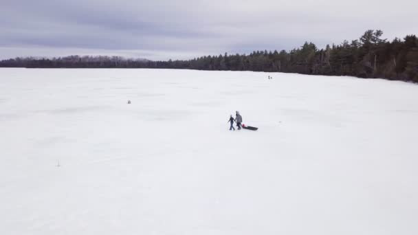 メイン州フィッツジェラルド池での氷釣りの空中ビューを取得します ３人が氷の上を歩いている — ストック動画