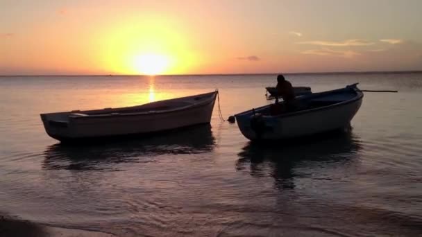 漁師と熱帯の夕日で海岸近くにドッキング小型ボート — ストック動画