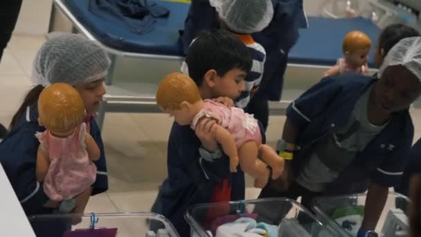 Crianças Vestidas Médicos Manipulando Bonecas Pequenas Com Orientação Adulto Editorial — Vídeo de Stock