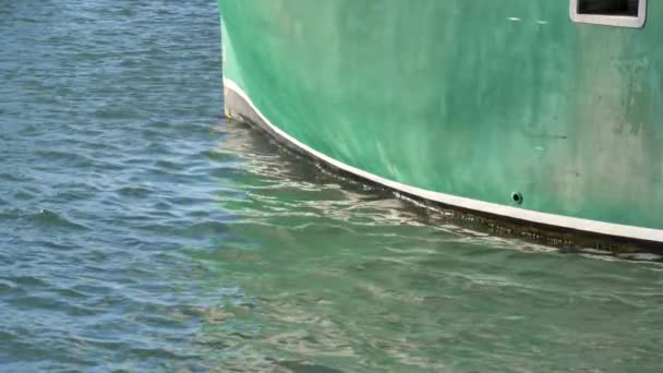 Zeitlupenaufnahme des Bugs eines großen Schiffes vor Anker in der Nähe der Magdlaen-Inseln in Quebec, Kanada. Der blau-grüne Rumpf entspricht der Farbe des Wassers.