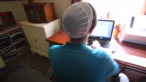 肩越しにコンピューターで働くメノナイトの女性を見て — ストック動画