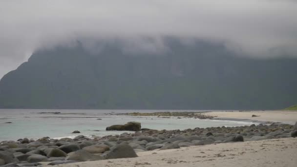 ノルウェーのウンスタードの海岸の景色 海は低い雲で覆われている 海岸沿いの観光客がテントを張っている 背後の急な丘との距離に家 — ストック動画