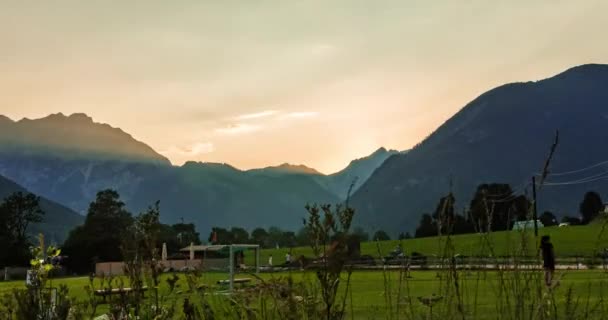 子供たちがサッカーをしている間 アルパイン山の後ろに太陽を沈める時間経過 — ストック動画