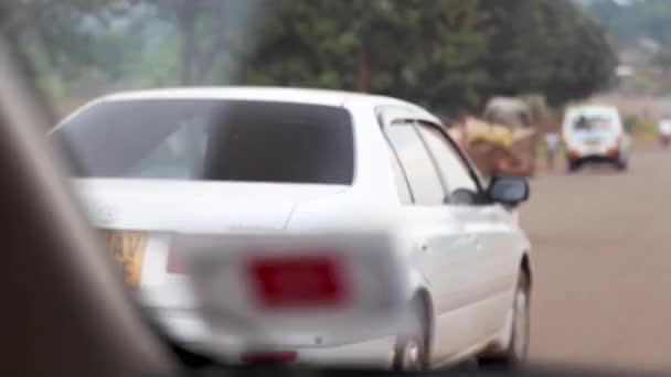 アフリカのウガンダの高速道路をタクシー そしてそれに結び付けられた必需品で自転車に乗っている男を通り過ぎました — ストック動画