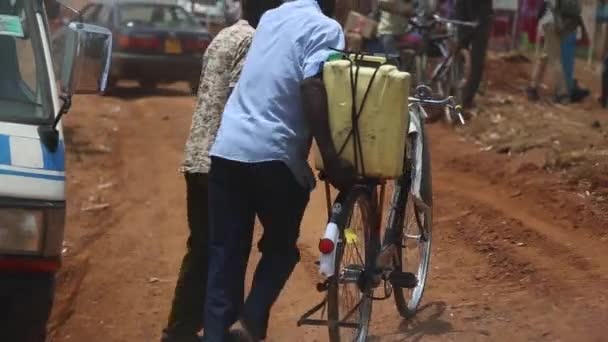 Afrikaanse Man Wandelen Fiets Met Jerrycan Gebonden Aan Rug Langs — Stockvideo