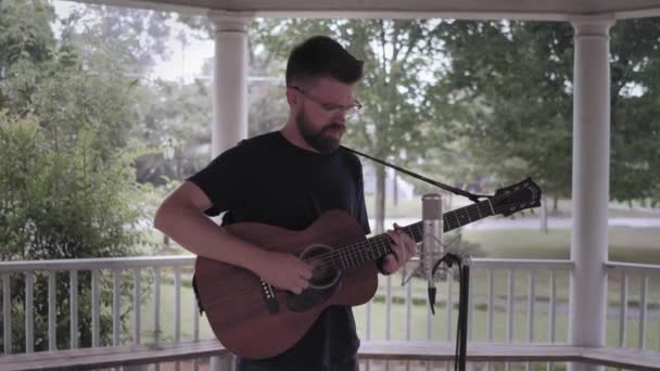 Man Playing Guitar Singing Gazebo Rain Push Out Shot Side — Stock Video