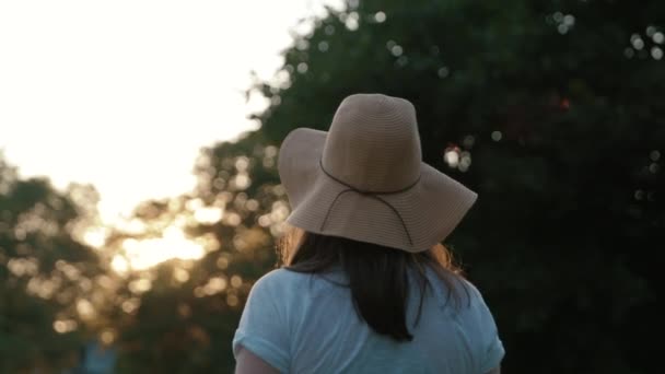 女の子でSunhat見るオフに日没前に振り向いてカメラに直面するスローモーション — ストック動画